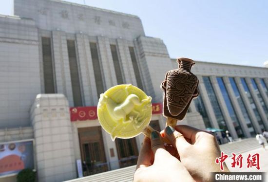 2021年7月30日，游客手拿“銅奔馬”“彩陶瓶”造型的雪糕，在甘肅省博物館前拍照打卡?！「哒?攝
