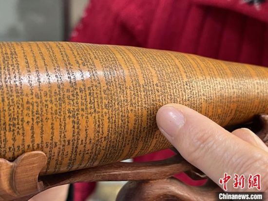 圖為長(zhǎng)約二十公分的長(zhǎng)條葫蘆雕刻佛教經(jīng)文作品。　張婧 攝