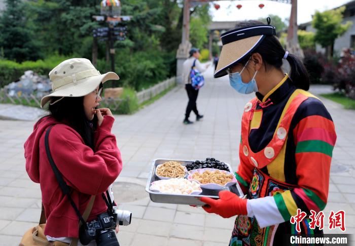 圖為身穿土族服飾的女性介紹當(dāng)?shù)靥厣〕浴！⊙Φ?攝