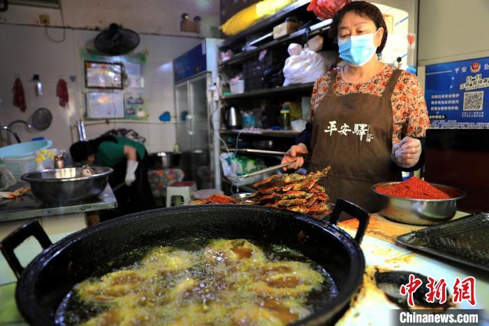 圖為平安驛·河湟民俗文化體驗(yàn)地內(nèi)的商戶炸干板魚?！⊙Φ?攝