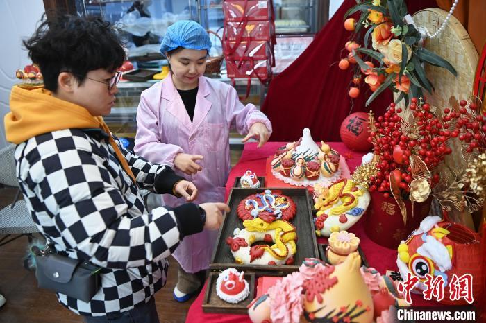 1月25日，隨著春節(jié)臨近，蘭州一花饃店“龍”元素花饃熱銷。圖為工作人員向顧客推薦“龍”元素花饃。九美旦增 攝</p><p>