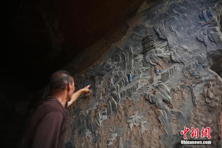7月15日，甘肅省平?jīng)鍪袥艽h百里石窟長廊羅漢洞石窟內(nèi)，該窟文保員郭建平介紹窟內(nèi)石刻彩繪壁畫。郭建平家中三代人曾自發(fā)保護羅漢洞石窟。羅漢洞石窟遺存40余個窟龕，以北魏至清代風格為主。中新社記者 李亞龍 攝