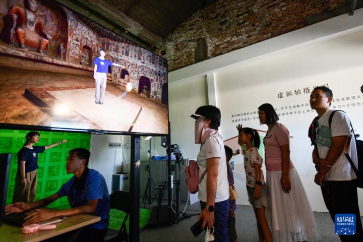 7月22日，游客體驗(yàn)“尋境敦煌——數(shù)字敦煌沉浸展”后，在虛擬演播廳拍攝一段真人與洞窟虛擬場景交互的視頻。新華社記者 郎兵兵 攝</p>
<p>