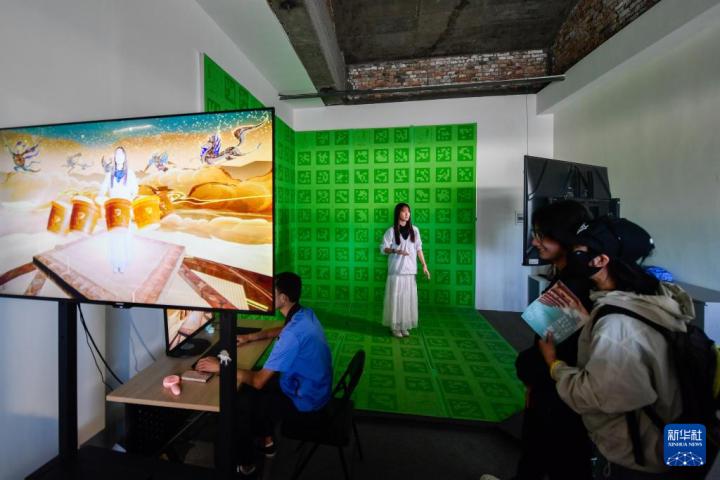 7月22日，游客體驗(yàn)“尋境敦煌——數(shù)字敦煌沉浸展”后，在虛擬演播廳拍攝一段真人與洞窟虛擬場景交互的視頻。新華社記者 郎兵兵 攝</p>
<p>